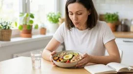 Una persona seduta a tavola che pratica l'alimentazione consapevole, osservando il cibo con calma invece di mangiarlo impulsivamente.