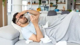 Uomo a letto con termometro per la febbre