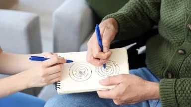 Persona anziana che scrive su un foglio - Segnali precoci Parkinson micrografia